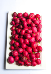 red radishes in a porcelain dish and on white background