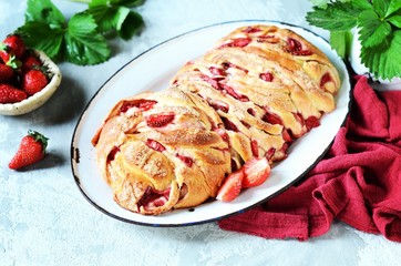 Yeast babka with strawberries and sugar in a dish on a gray background