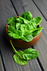 Spinach leaves in wooden bowl on dark wooden table background. Healthy vegan food trend. Vegan lifestyle concept.