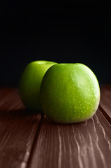 Fresh green apples on dark rustic woden background.