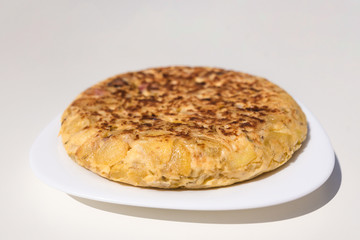 Close up view of an authentic homemade Spanish omelette made with eggs, potatoes and bacon. Traditional Spanish cuisine. Food and gastronomy concept. Homemade and traditional. White background.