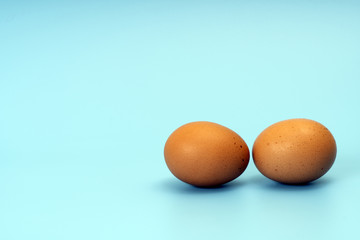 Two brown chicken eggs on a turquoise background, image with copy space