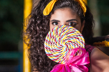 Close up of a beautiful teenager holding a giant lollipop in the park. Focus on the lollipop