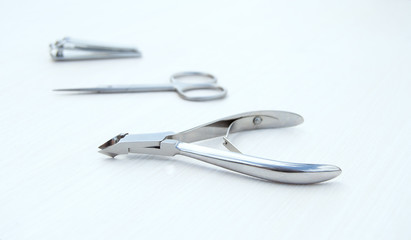 Metal accessories for manicure. Cuticle clippers, small cuticle scissors and nail nippers on a white background.