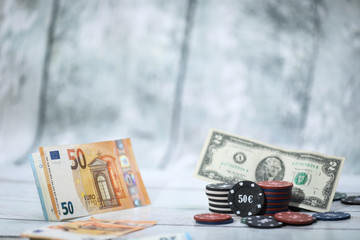Poker playing chips in focus in front on a wooden table and wooden background Online gambling. Addiction. Falling poker chips and money in blur . Falling money. Losing money