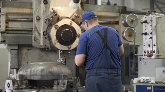 Milling machine operator working in factory workshop. Cutter cuts metal workpiece. shavings twisted into spiral. Metal working milling machine. Produces metal detail in factory.