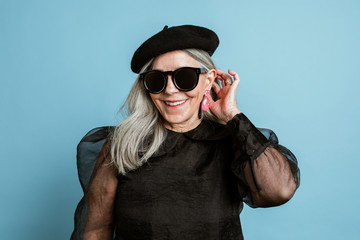 Beautiful senior woman in a cool beret and sunglasses