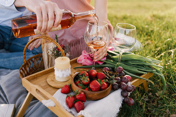 Picnic basket with strawberries, grapes and buns on the green grass in the garden