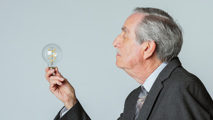 Senior businessman holding a light bulb in a profile shot