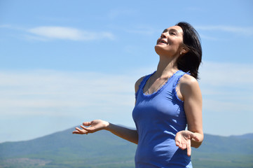 Fototapeta na wymiar Young brunette woman with her head raised to the sky smiling with teath and enjoying freedom. sunny summer day