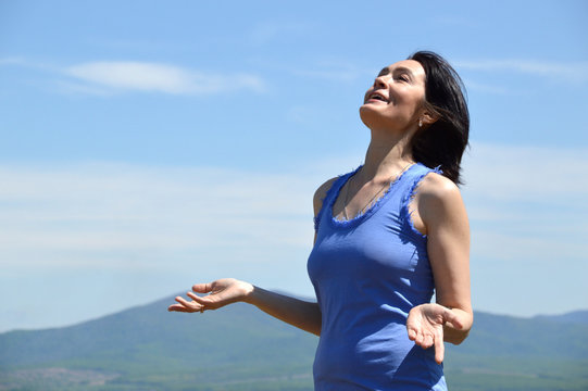 Young brunette woman with her head raised to the sky smiling with teath and enjoying freedom. sunny summer day