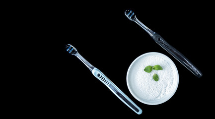 Toothbrushes and tooth powder on a black background with mint leaves. Mortgage the apartment.