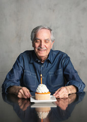 Senior man celebrating with a birthday cupcake