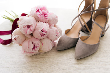 Beautiful Bridal bouquet of pink peonies next to the bride's shoes