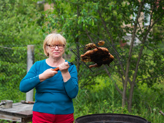Senior Caucasian woman holding barbecue grilled chicken
