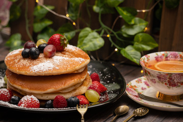 Stack of pancakes with fresh fruit and maple syrup