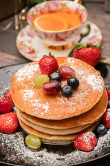 Stack of pancakes with fresh fruit and maple syrup