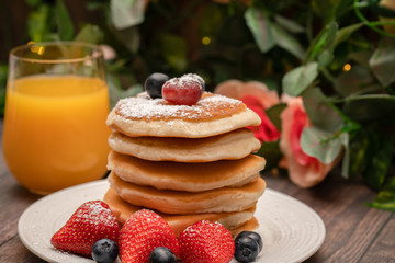 Stack of pancakes with fresh fruit and maple syrup