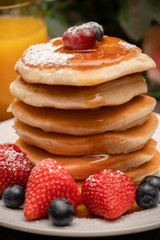 Stack of pancakes with fresh fruit and maple syrup