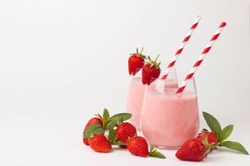Glass of fresh strawberry milkshake, smoothie and fresh strawberries on pink, white and wooden background. Healthy food and drink concept.