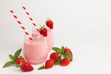 Glass of fresh strawberry milkshake, smoothie and fresh strawberries on pink, white and wooden background. Healthy food and drink concept.