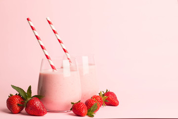 Glass of fresh strawberry milkshake, smoothie and fresh strawberries on pink, white and wooden...
