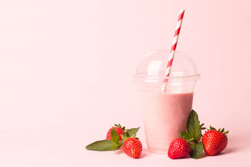 Glass of fresh strawberry milkshake, smoothie and fresh strawberries on pink, white and wooden background. Healthy food and drink concept.