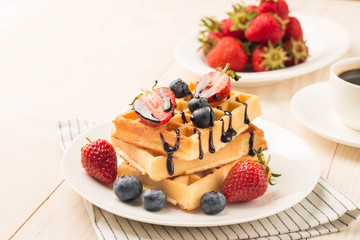 Fresh homemade food of berry Belgian waffles with honey, chocolate, strawberry, blueberry, maple syrup and cream. Healthy dessert breakfast concept with juice