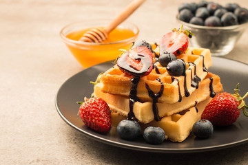 Fresh homemade food of berry Belgian waffles with honey, chocolate, strawberry, blueberry, maple...