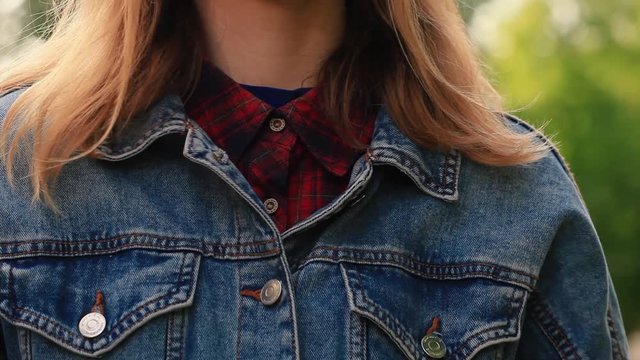 the girl unzips the button of her denim jacket and then zips it back up