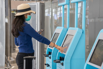Backpacker travelers Asian women wearing masks covid19 disease Prevention and Check-in, ticket issuing, boarding pass, automatic at the airport terminal.New normal and travel concept.