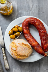 portuguese smoked sausage, olives and corn bread broa on ceramic background