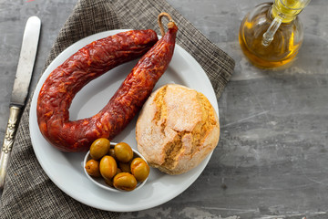 portuguese smoked sausage, olives and corn bread broa on ceramic background