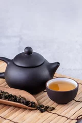 Foto op Aluminium Hot tea in black teapot and cups and dry tea leaves over bright gray cement background, close up, copy space design concept. © RomixImage