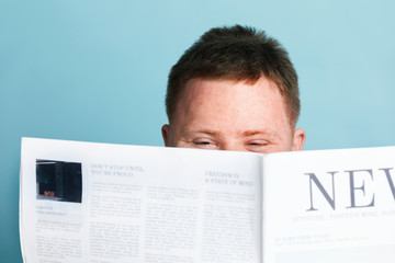 Fototapeta na wymiar Boy with down syndrome reading a newspaper during the coronavirus pandemic