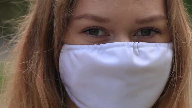 a girl in a white mask is standing on the street. close up.