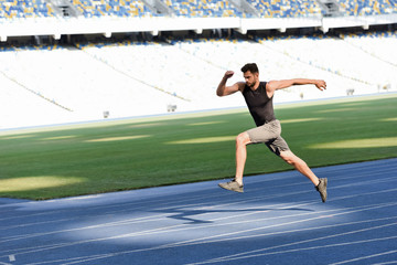 fast handsome runner exercising on running track at stadium