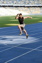 Fototapeta na wymiar fast handsome runner exercising on running track at stadium