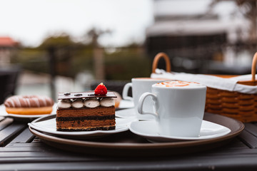 cup of a fresh caramel latte with whipped cream on the table and chocolate cake.