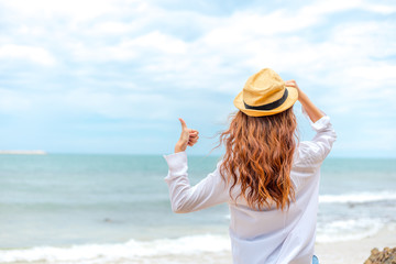 smiling young woman in sun hat and finger thumb up on beach. summer, holidays, vacation, travel concept