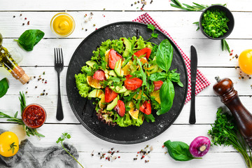 Healthy food: salad of arugula, avocado, strawberry and orange. Top view. Free space for your text.