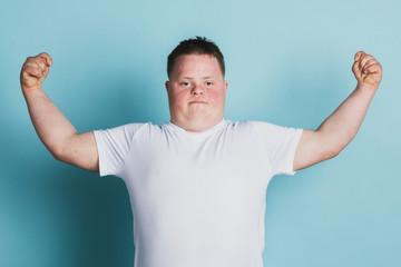 Proud boy with down syndrome flexing his arms