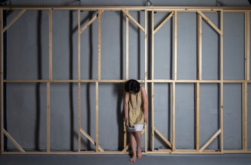 sad woman sandwiched in wooden tesky in an empty room