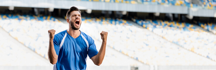 emotional professional soccer player in blue and white uniform showing yes gesture at stadium,...