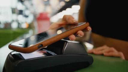 Mobile NFC payment for order in gym cafe. Hand of woman customer paying through mobile phone over pos terminal. money transfer through smartphone app. Apple pay concept