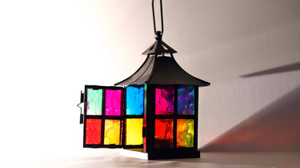 lantern in the form of a house with colorful bright Windows  with a burning candle on a white background