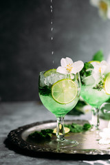 Cold cocktail with mint, lime and ice in a glass