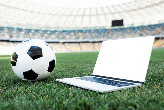 Soccer Ball And Laptop With Blank Screen On Grassy Football Pitch At Stadium