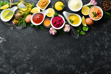 Set of sauces and spices on stone background. Sauces: mayonnaise, ketchup, tartare, barbecue and chili sauce in bowls.