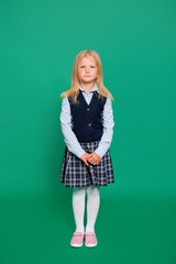 Young girl in school uniform posing on a green background.